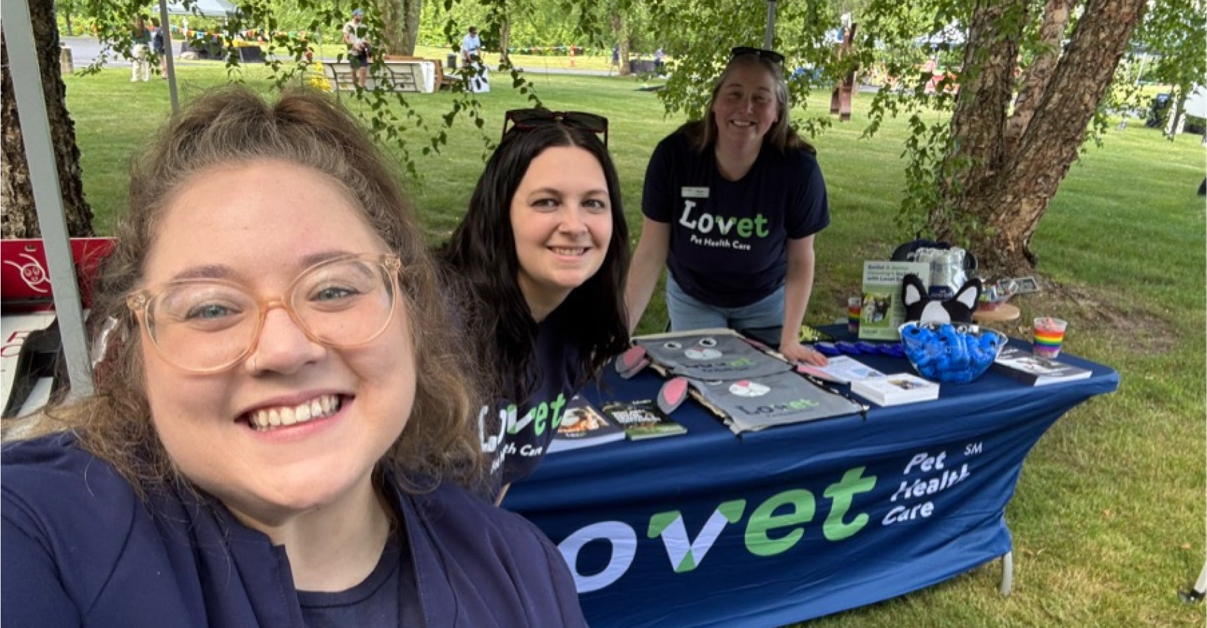 Three smiling Lovet team members gather behind a branded table at the Humane Society of West Michigan’s 143rd birthday party.