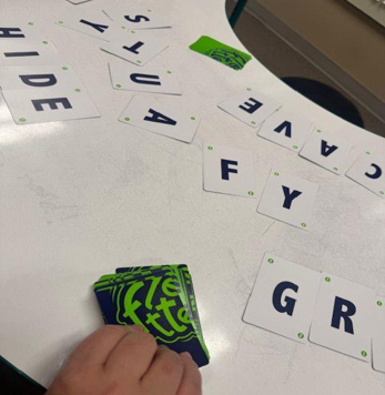 A student arranging letter tiles on a worksheet.