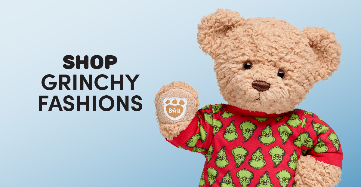 Holiday-themed email featuring a family gathered around a book with Build-A-Bear The Grinch plush characters and Max the dog plush beside them. The Grinch logo appears above the headline TIS THE SEASON TO BE GRINCHY, followed by the text Even the grouchiest names on your list will love these Grinch gifts! and a red SHOP NOW button. Below, product sections showcase a Grinch plush in a Santa outfit with the text SHOP GRINCH and an Extra Large Heart badge, Max the dog plush with SHOP MAX, a Giant Grinch plush with an Extra Large Heart badge and SHOP GIANT GRINCH, and a teddy bear wearing Grinch-print pajamas with SHOP GRINCHY FASHIONS. A red
 SHOP COLLECTION button appears at the bottom.
