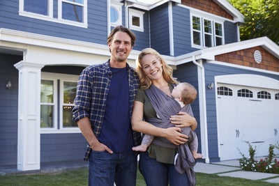 A smiling family in front of their home