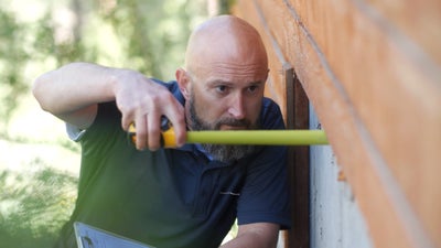 Inspector measuring a crawl space door.