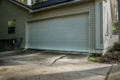 Cracking and uneven driveway in front of garage.
