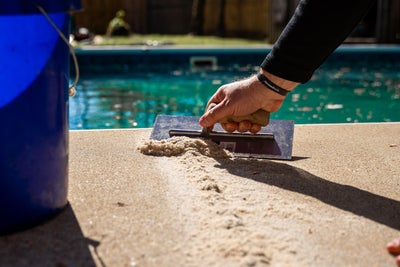 man smoothing concrete pool deck with tool