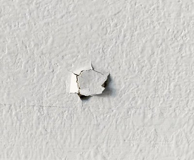 Close up of a nail pop appearing from drywall.