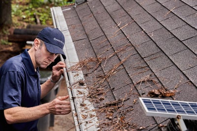 Groundworks crewman checking the gutters on a home.