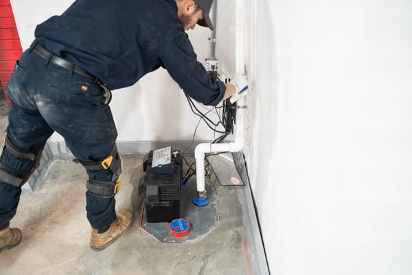 Man installing a sump pump in the corner of a basement
