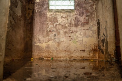 A basement with water in it, destroying the foundation as it moves through the basement.