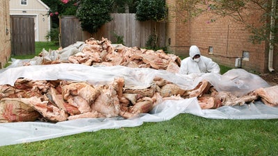 man beside large pile of fiberglass insulation in grass outdoors