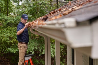 man inspecting clogged gutters
