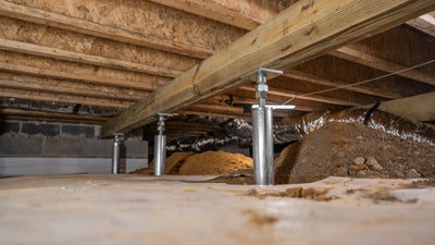 Three crawl space support jacks attached to a wooden beam in a crawl space.