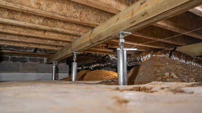 three crawl space supports holding up a wooden beam inside crawl space