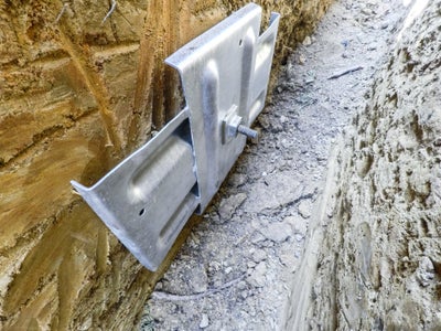 A wall anchor attached and to a basement wall.