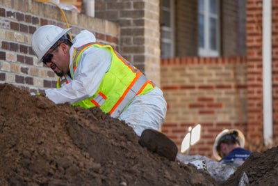 crew backfilling soil around a house