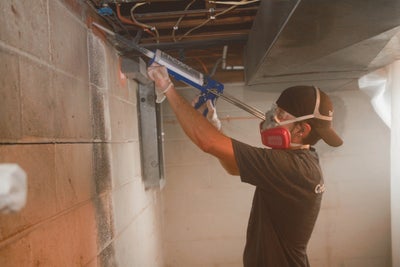 A Groundworks professional sealing cracks in the basement of this home to keep the radon out.
