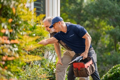 Employee helping show homeowners overgrown bushes