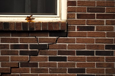 Close up of cracks in bricks on the exterior of a home.