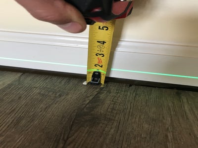 A measuring tape next to a floor and wall to show sagging floors.