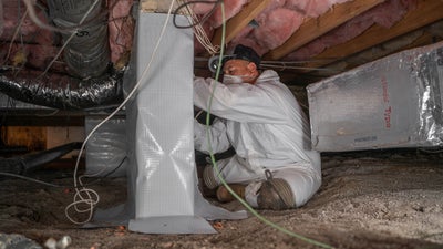 Crewman installing a crawl space vapor barrier.