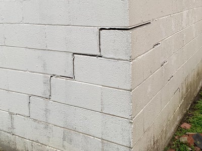 Exterior of a leaning wall causing a bowing basement wall.