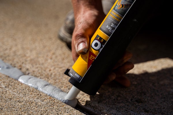caulk gun sealant on concrete crack