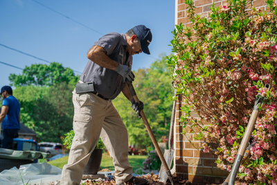 worker digging near foundation landscaping