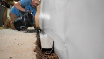 A man installing Basement Gutter in a basement.