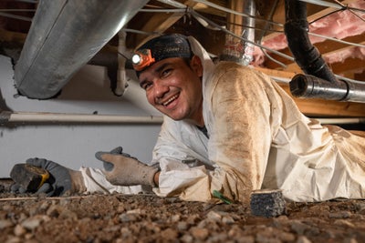 A Groundworks worker in a crawl space excited about resolving humidity problems.