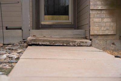 Uneven concrete steps in a front yard.