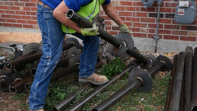 Helical pier being lifted by installer.
