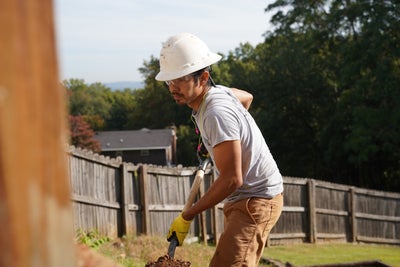 crew member digging ground soil with shovel