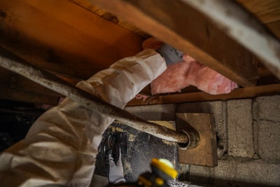CFI tech repairing wet crawl space insulation in crawl space of a home