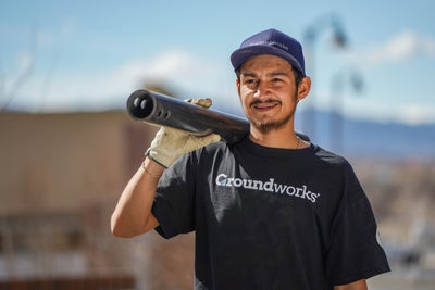 Groundworks crew member carrying pipe