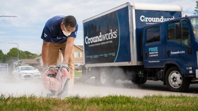 Groundworks truck and crew member sanding concrete driveway