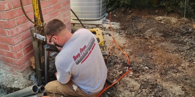 Bay Area Underpinning technician placing pier below soil next to a house.