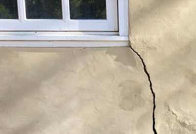 Large crack on house exterior near window