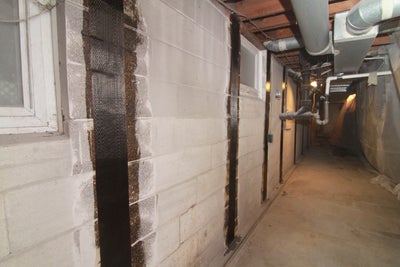 Carbon fiber straps on a block wall.