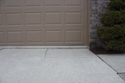 Uneven driveway with a crack in the corner.