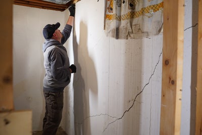 inspector checking basement walls for cracks