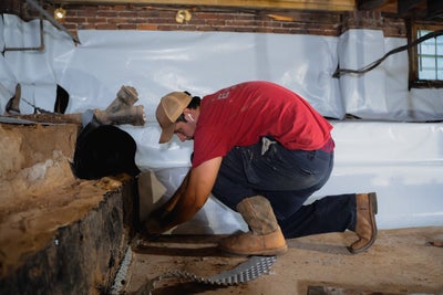 Installer placing vapor barrier onto basement walls.