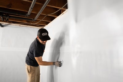 JES installer wiping down a basement wall with a rag.