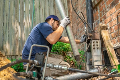 Technician attaching foundation pier to a home's foundation.