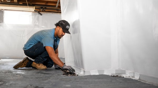 Crew installing basement waterproofing in home