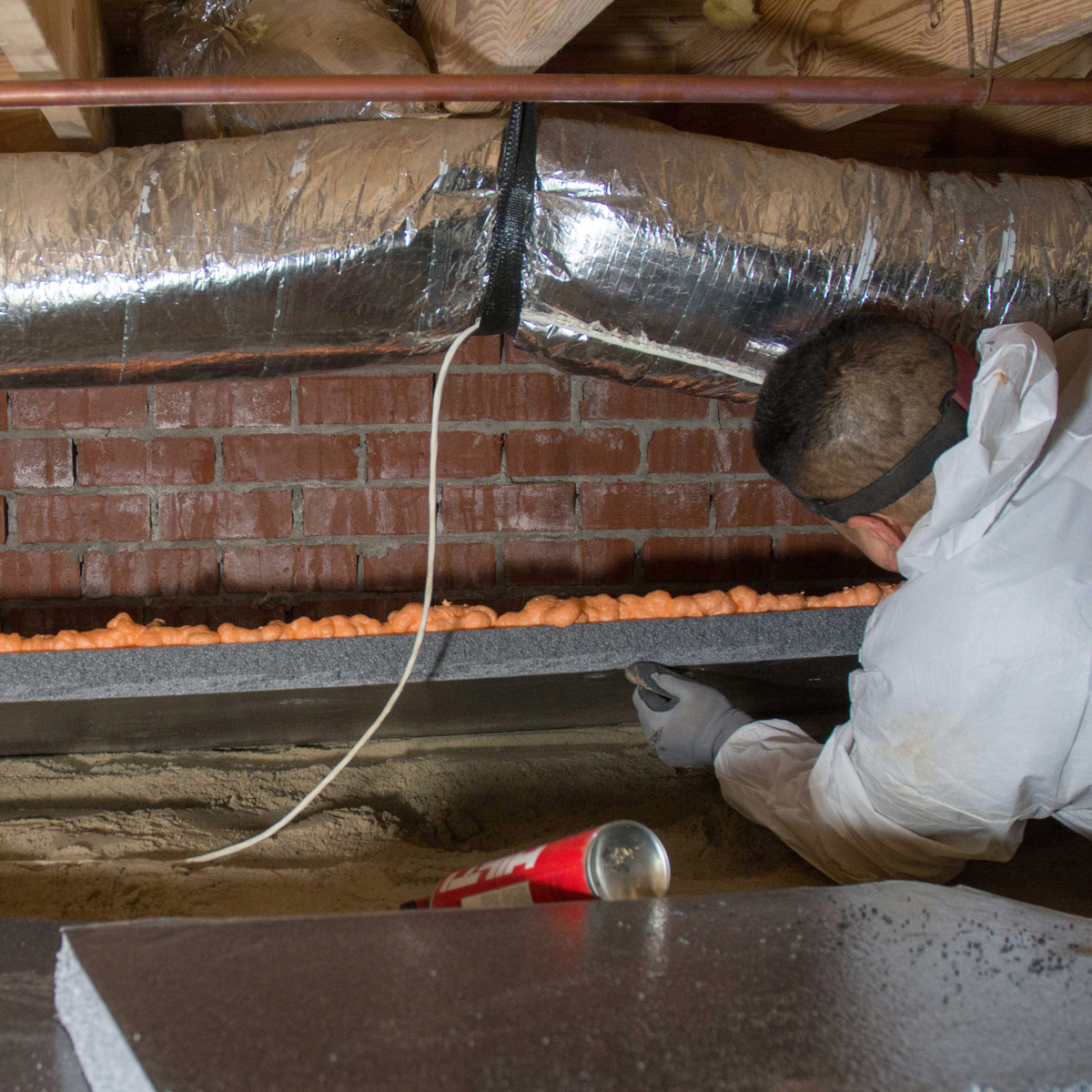 A Groundworks worker installing insulation in a crawl space.