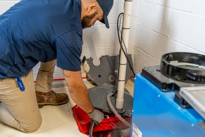 service technician testing and cleaning a sump pump system