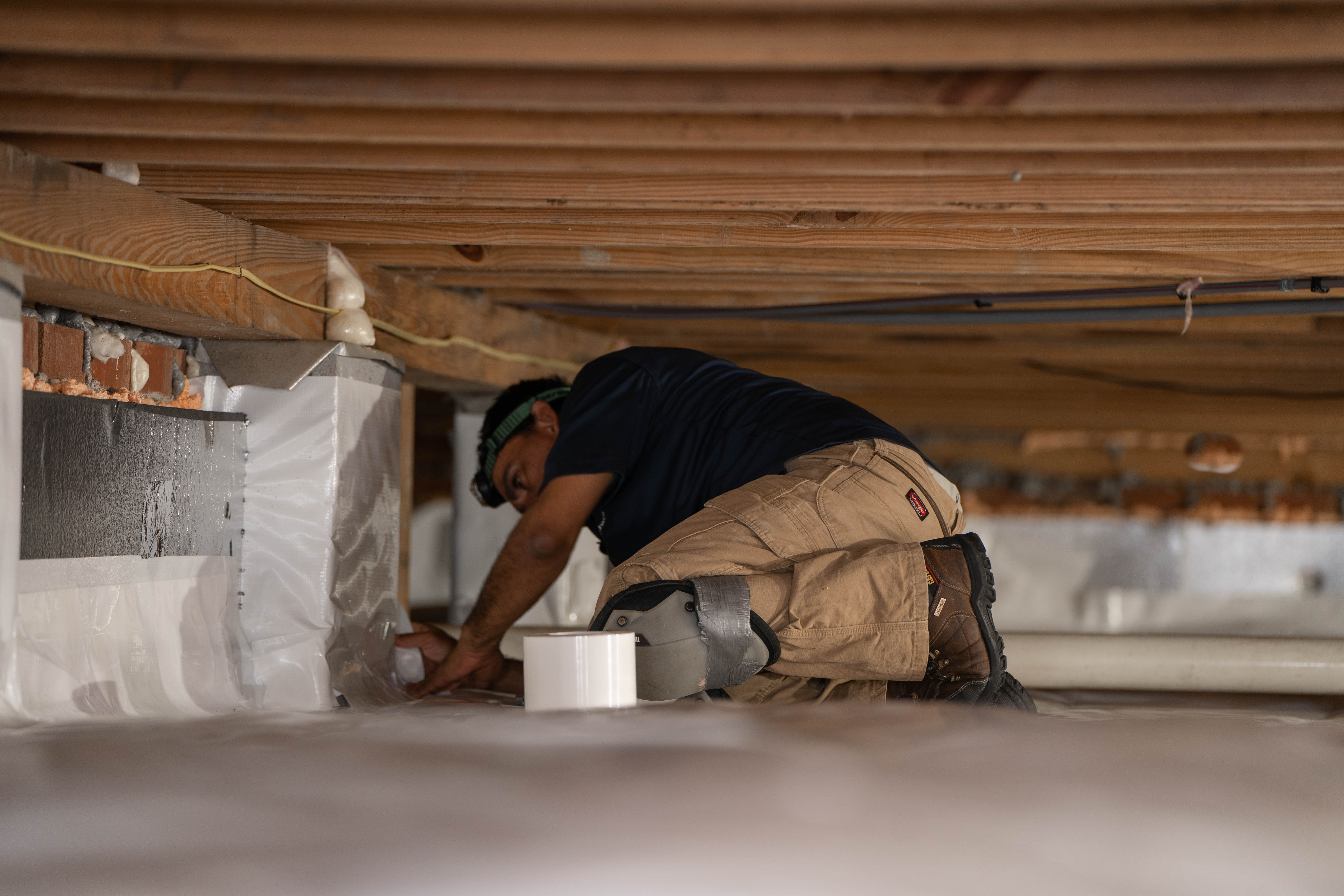 Man on knees installing vapor barrier