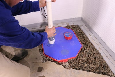Man installing sump pump in a basement.