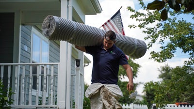 crew member carrying a roll of crawl space drainage matting