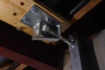 a hinge that connected to a metal beam and a wooden 4x4
