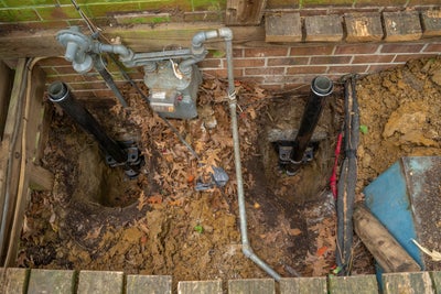 Push piers being attached to foundation footing, excavated ground.