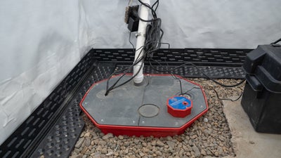 Fully installed sump pump in the corner of a basement.